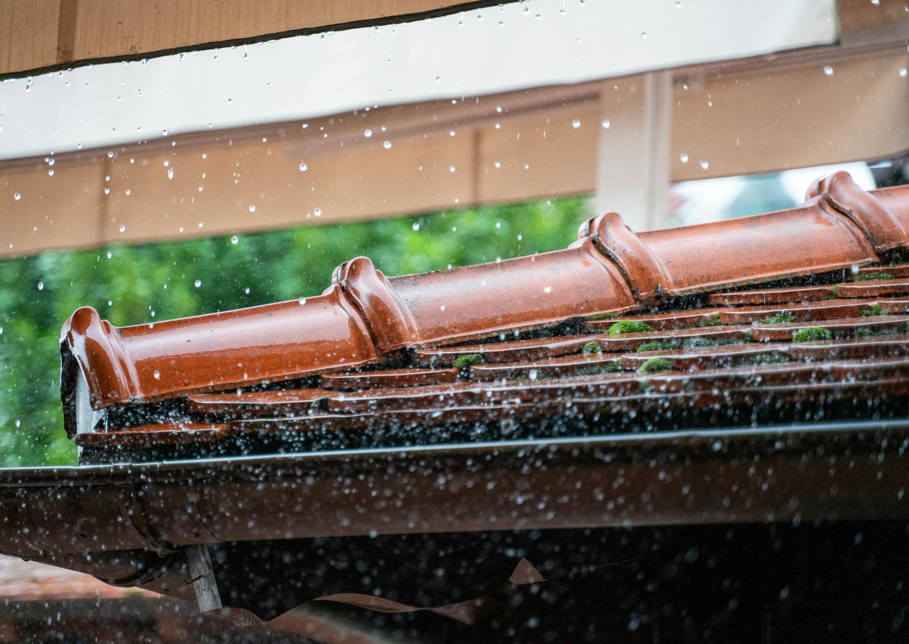 Krople deszczu spływające z dachówki podczas intensywnego opadu