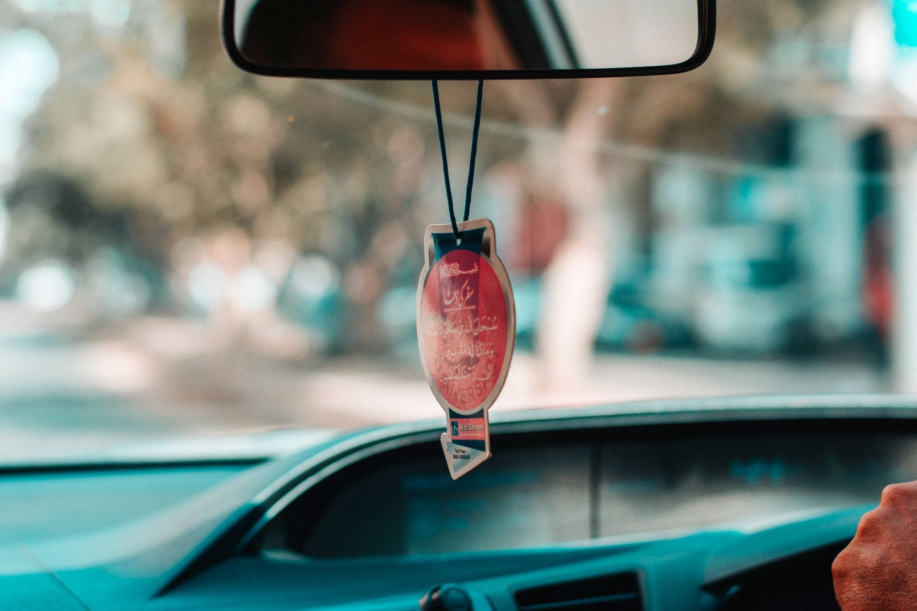 Jak wybrać praktyczne akcesoria do auta, które naprawdę ułatwiają codzienną jazdę Wnętrze auta z wiszącą ozdobą i rozmazaną drogą w tle