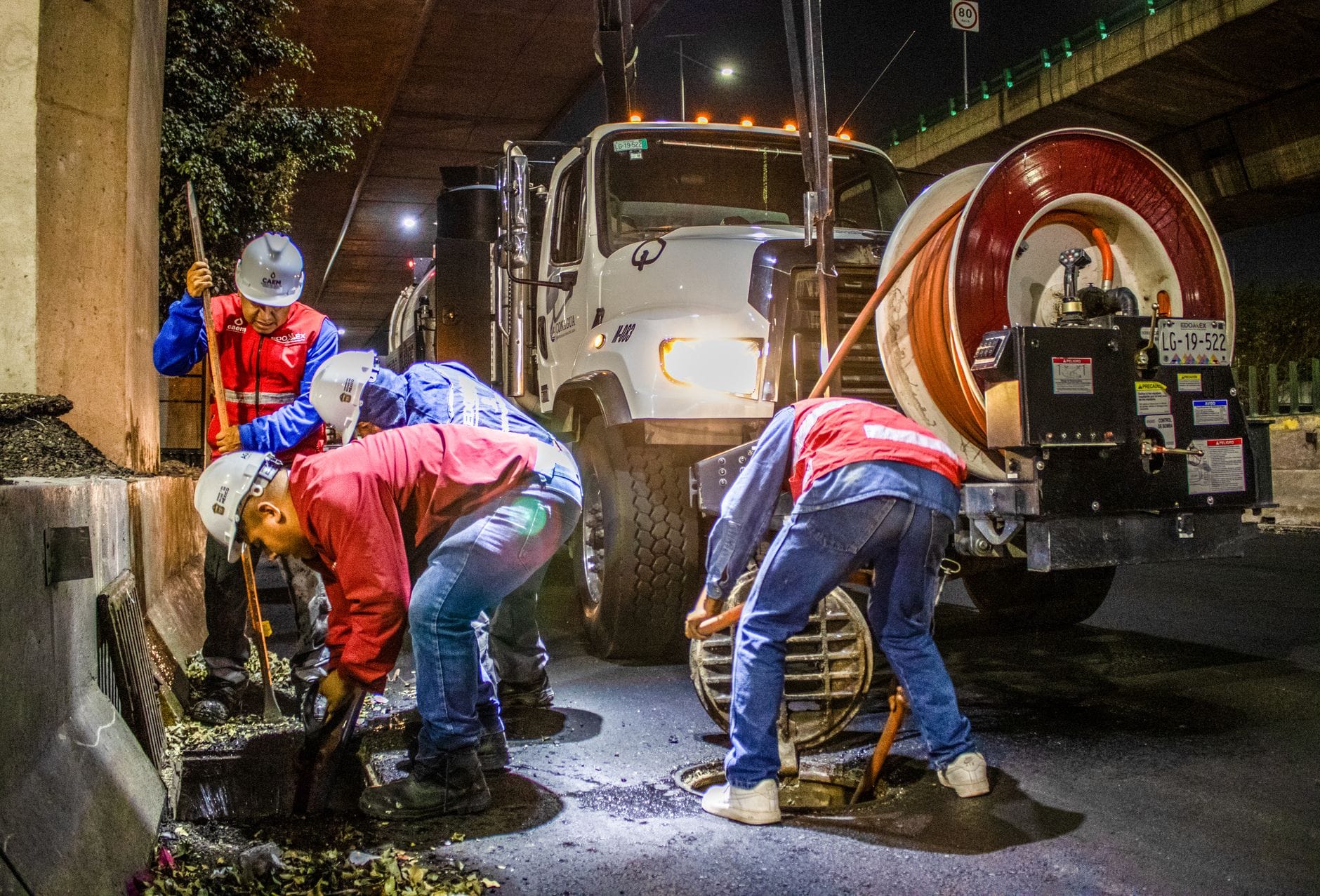 Pracownicy nocą czyszczą kanalizację pod mostem specjalną maszyną